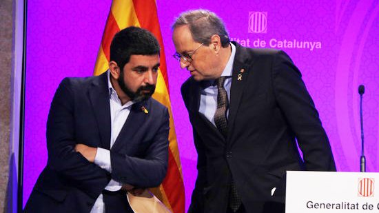 Pla mitjà del president del Govern, Quim Torra, parlant amb el conseller Chakir El Homrani durant la roda de premsa pel coronavirus. Imatge del 12 de març del 2020