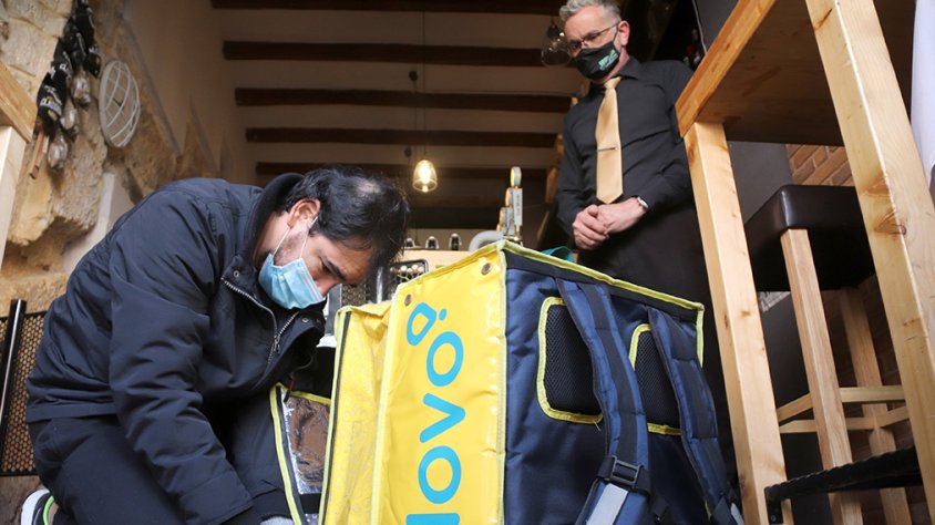 Primer pla d'un repartidor de menjar a domicili carregant una comanda.