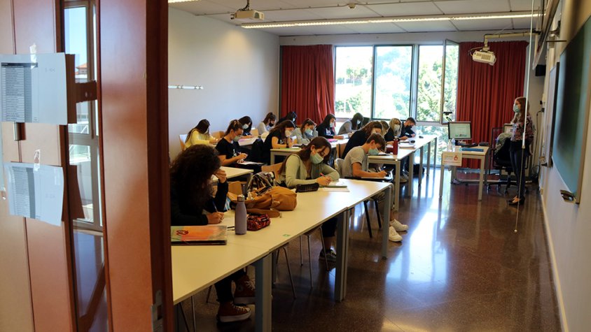 Pla obert d'una aula de la URV, vista des de fora, amb alumnes fent classe amb mascareta en el primer dia del curs 2020-2021.