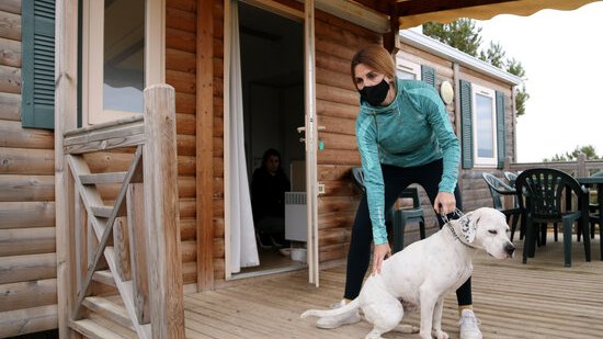 Pla obert d'una turista i el seu gos a l'exterior d'un dels bungalous del càmping Montblanc Park Capfun. Imatge del 27 de març del 2021